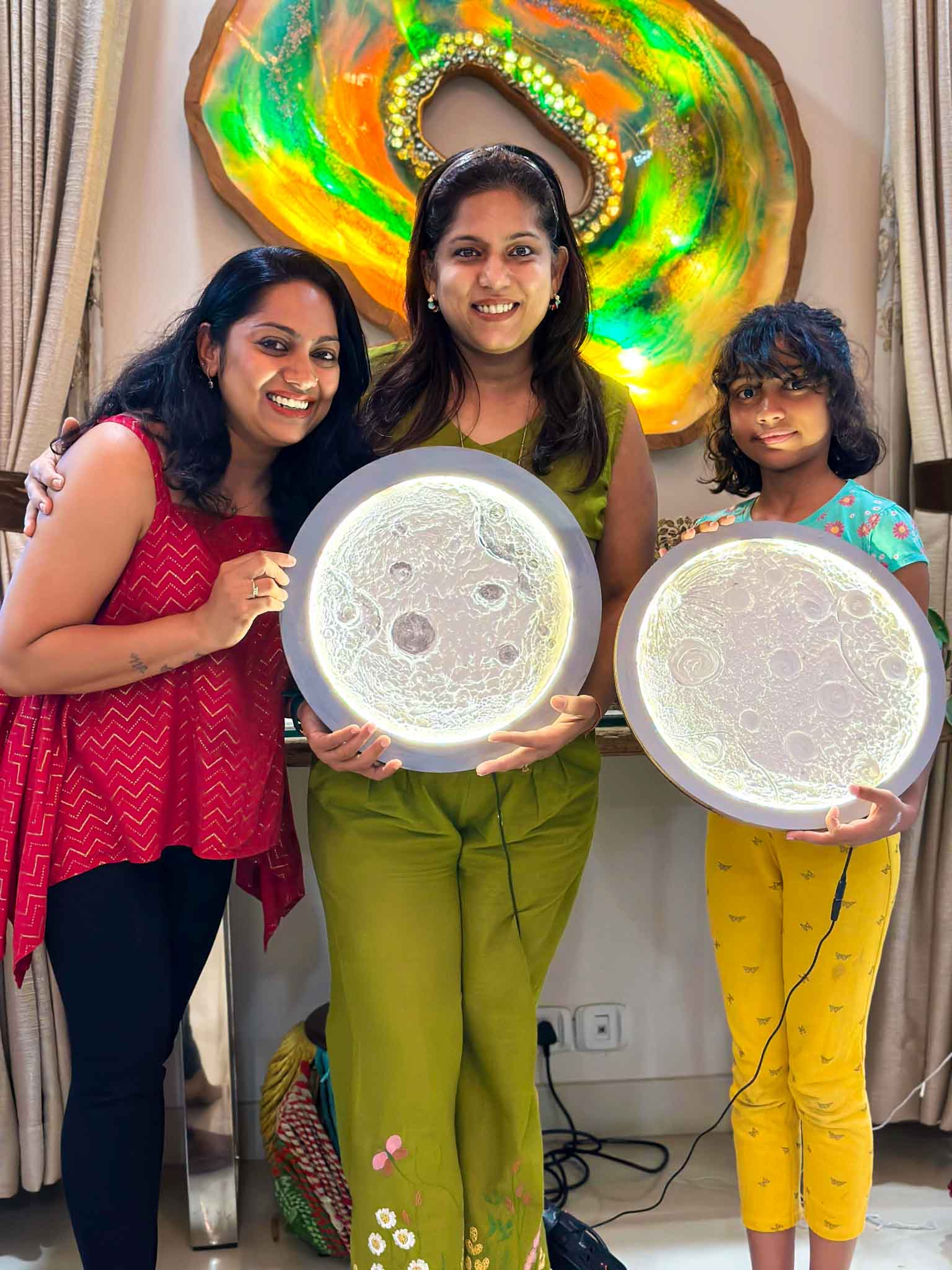 Three participants smiling and proudly holding their finished glowing moon lamps.